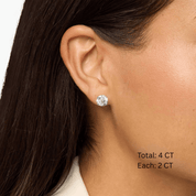 Round-cut moissanite stud earrings worn on the ear, 4 ct per pair with 2 ct per stone.