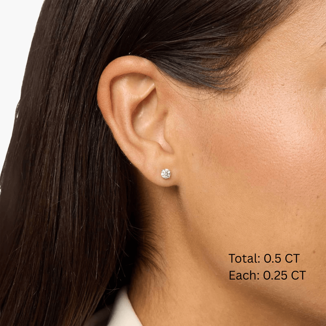 Round-cut moissanite stud earrings worn on the ear, 0.5 ct per pair with 0.25 ct per stone.