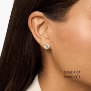 Round-cut moissanite stud earrings worn on the ear, 4 ct per pair with 2 ct per stone.