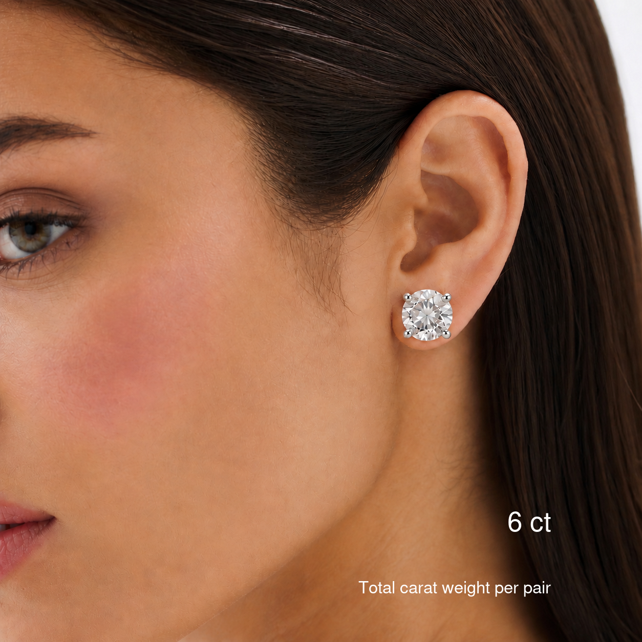 Round-cut moissanite stud earrings in white gold worn on a model, 6 ct total carat weight per pair.