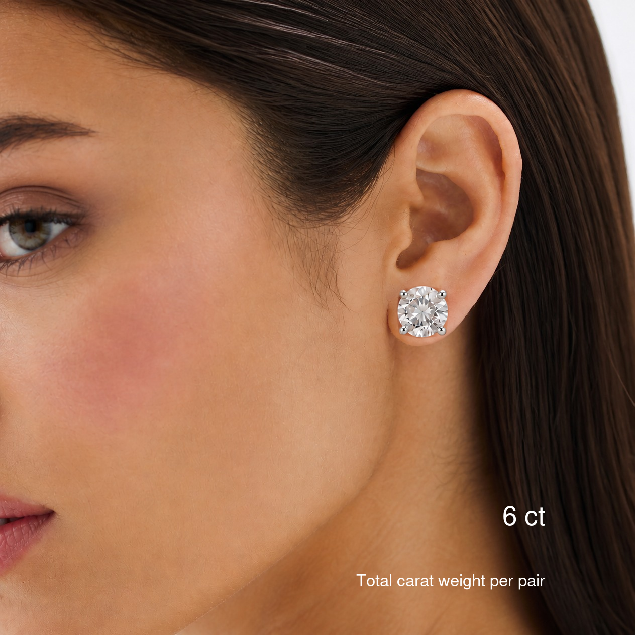 Round-cut moissanite stud earrings in white gold worn on a model, 6 ct total carat weight per pair.