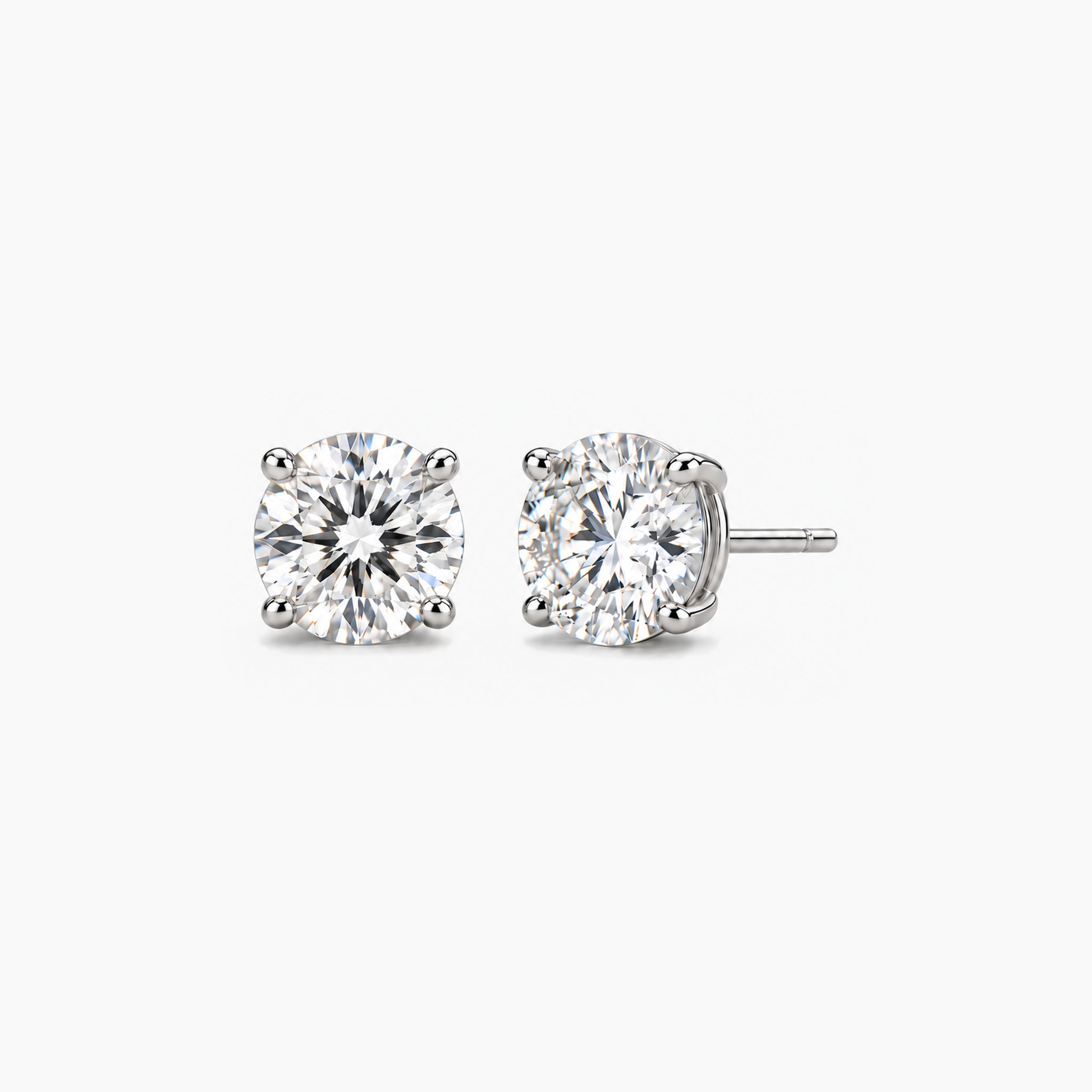 Round-cut moissanite stud earrings in white gold vermeil, front and three-quarter views.