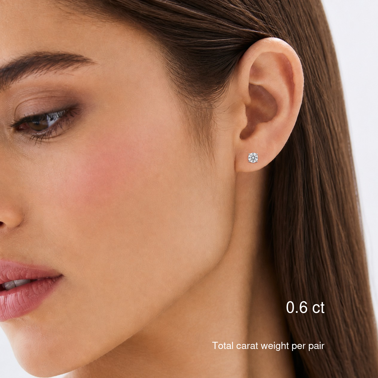 Round-cut lab-grown diamond stud earrings in white gold worn on a model, 0.6 ct total carat weight per pair.