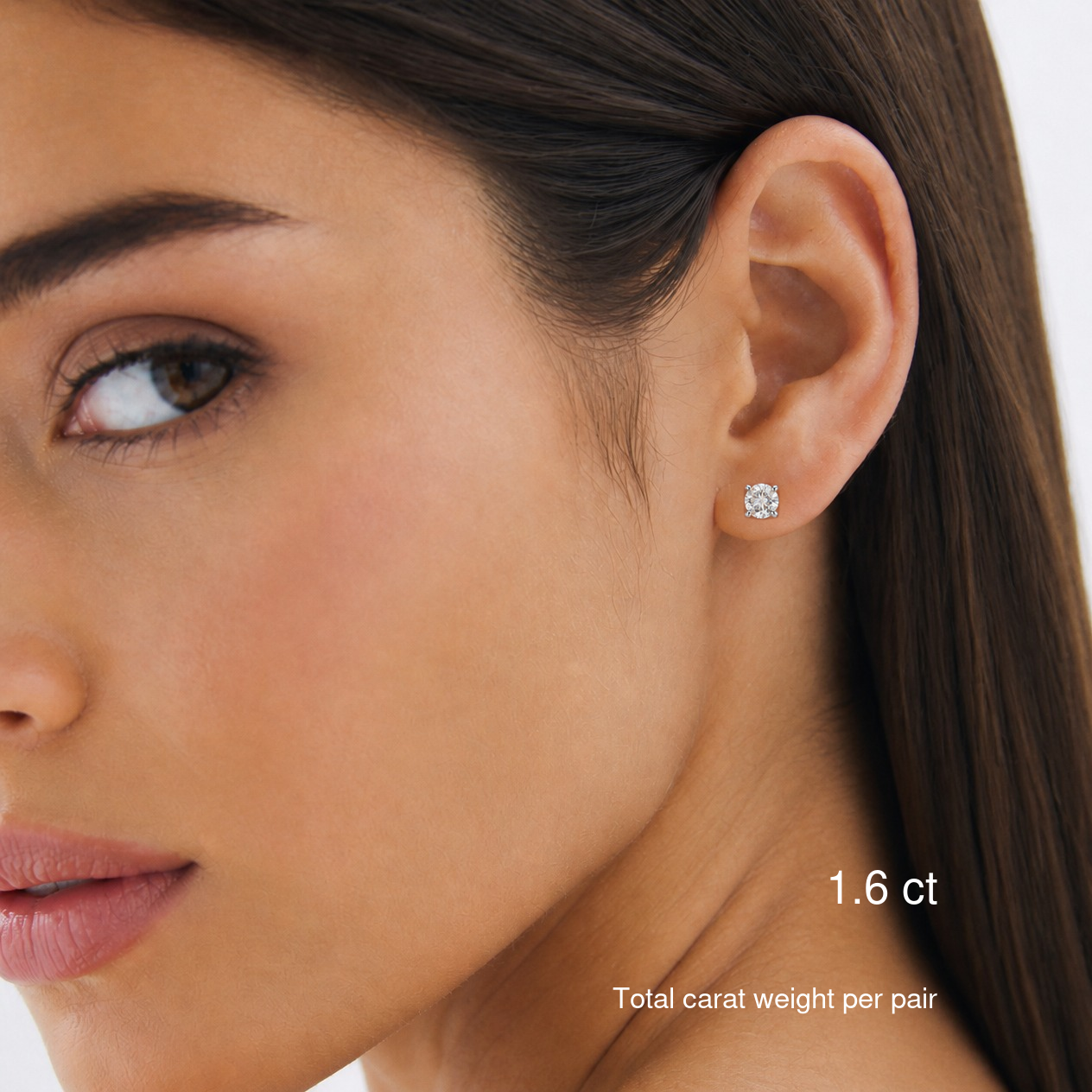 Round-cut moissanite stud earrings in white gold worn on a model, 1.6 ct total carat weight per pair. Natural bright portrait.